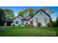 Charming white brick home with dark trim, landscaped yard and a well-manicured lawn at 8271 Camelia Ln, Denver, NC 28037