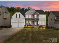 Beautiful two-story home featuring a manicured lawn, stone accents, and a two-car garage at 8453 Mossy Cup Trl, Harrisburg, NC 28075