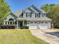 Charming two-story home with blue siding, a well-manicured lawn, and an attached two-car garage at 12100 Bay Tree Way, Charlotte, NC 28277