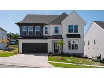 Charming two-story home with a black garage, black trim, and landscaped front yard at 16013 Moxie Glen Ct, Charlotte, NC 28278