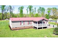 Charming single-story home featuring red roof and cozy front porch in a serene, wooded setting at 161 Hickory Nut Dr, Statesville, NC 28677