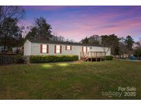Charming single-story home featuring red shutters, a cozy front porch, and a spacious, green front yard at 189 Woodwinds Dr, Mooresville, NC 28115