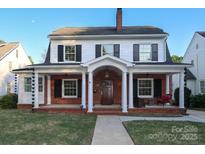 Charming two-story home with brick facade, inviting front porch with white columns and classic black shutters at 2015 Dilworth E Rd, Charlotte, NC 28203
