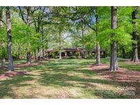 Charming single-story home featuring a spacious front yard with mature trees, creating a serene and private setting at 2415 Hargette Rd, Monroe, NC 28112