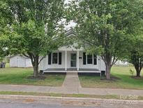 Charming single story home with white siding and a covered front porch, framed by mature trees at 301 E 11Th St, Kannapolis, NC 28083