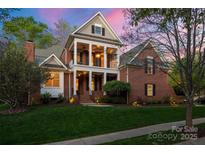 Stately two-story brick home featuring a welcoming front porch with elegant columns and manicured landscaping at 3301 Mcpherson St, Waxhaw, NC 28173