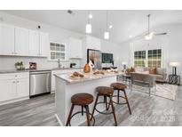 Bright kitchen features a large island with seating, stainless steel appliances, and an open layout to the living room at 5828 Patton St, Charlotte, NC 28269