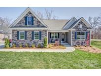 Charming single-story home with stone facade, blue shutters, covered porch, and well-manicured lawn at Tbd Boomer Ct # 12, Statesville, NC 28677