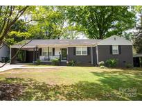 Charming single-story home featuring a covered porch, dark brick facade, and lush green lawn at 1126 E. Woodlawn Rd, Charlotte, NC 28209