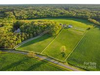 An aerial view of a horse farm with green pastures, a pond, stables, and mature trees surrounding the property at 15670 Bethel Avenue Ext, Midland, NC 28107