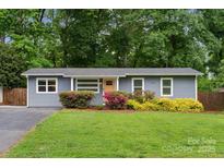 Charming single-story home with a well-manicured lawn, vibrant landscaping and a welcoming yellow door at 3725 Dunwoody Dr, Charlotte, NC 28215