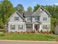 Beautiful two-story home with gray siding, black shutters, manicured lawn and landscaping at 811 Penny Royal Ave, Fort Mill, SC 29715