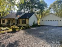 Quaint ranch-style home featuring a welcoming front porch, detached garage, and a well-maintained gravel driveway at 109 Wilson Acres Dr, Kings Mountain, NC 28086