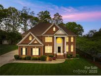Elegant brick home with a manicured lawn and classic architectural details at twilight at 130 Weeping Spring Dr, Mooresville, NC 28115