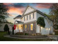 Charming two-story home with stone accents and a manicured lawn at sunset at 139 Autumn Grove Ln, Mooresville, NC 28115