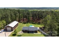 Aerial view of a home with a pool and barn surrounded by tall trees at 5381 Mount Carmel Rd, Heath Springs, SC 29058