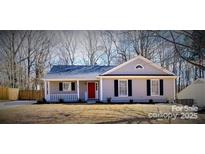 Charming single-story home with a welcoming front porch and a red front door and well maintained lawn at 7820 Elm Tree Ln, Charlotte, NC 28227