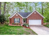 Charming single-story brick home with attached garage, manicured lawn, and mature trees providing shade at 1050 Emerson Dr, Mooresville, NC 28115