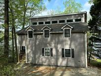 Gray two-story home with dormer windows, black shutters, and water view surrounded by mature trees at 1224 Island Creek Dr, Troy, NC 27371