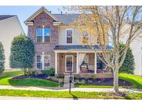Charming two-story brick home with a welcoming front porch and manicured landscaping at 15613 Troubadour Ln, Huntersville, NC 28078