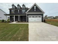 Beautiful two-story home with a gray exterior, manicured lawn, and attached two car garage at 3214 Mcharney Dr # 34, Harrisburg, NC 28075