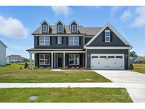 Charming two-story home featuring a well-manicured lawn, a two-car garage, and classic architectural details at 3214 Mcharney Dr # 34, Harrisburg, NC 28075