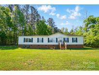 Charming one-story home featuring green shutters and a spacious yard, surrounded by lush trees and a bright blue sky at 3678 Old Camden Hwy, Heath Springs, SC 29058