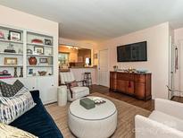 Inviting living room with a plush blue sofa, unique round ottoman, and built-in shelving at 557 Wakefield Dr # A, Charlotte, NC 28209