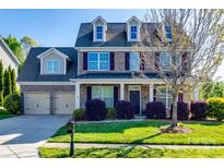Charming two-story brick home with a manicured lawn and inviting curb appeal on a sunny day at 5716 Langwell Ln, Charlotte, NC 28278