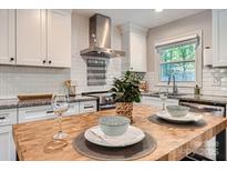 Bright kitchen featuring white cabinets, subway tile backsplash, stainless steel range hood, and butcher block island at 1702 Herrin Ave, Charlotte, NC 28205