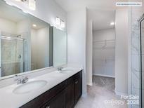 Bright bathroom featuring double sinks, a large mirror, and a walk-in shower with marble tile surround at 2579 Ruby Dixon Crossing Dr # 12, Gastonia, NC 28056