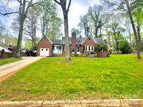 Charming brick home featuring a well-manicured front yard with mature trees and a single-car garage at 310 S Poston St, Shelby, NC 28150