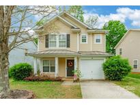 Charming two-story home featuring tan siding, black shutters, a cozy front porch, and a one-car garage at 523 Tribune Dr, Charlotte, NC 28214