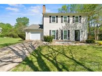 Charming home featuring a well-manicured lawn, black shutters and a paved driveway leading to an attached garage at 8719 Sweet Sage Ln, Charlotte, NC 28227