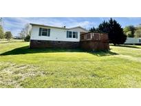 Two story home featuring a wooden porch, brick foundation, green shutters, and large front lawn at 105 Branson Dr, Olin, NC 28660