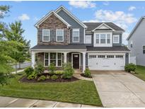 Charming two-story home with stone and siding facade, attached garage, and manicured front lawn at 12710 Es Draper Dr, Huntersville, NC 28078