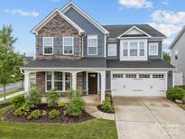 Charming two-story home featuring a stone facade, two-car garage, and well-manicured front yard at 12710 Es Draper Dr, Huntersville, NC 28078