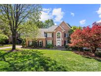 Beautiful two-story brick home with a well-manicured lawn and mature trees at 10609 Oak Pond Cir, Charlotte, NC 28277