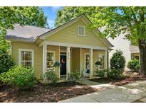 Charming home featuring a cozy front porch with columns and blooming flowers and mature trees at 19416 Fridley Ln, Cornelius, NC 28031