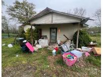 Shows a dilapidated house with peeling paint, debris, and overgrown vegetation in disrepair and in need of renovation at 2702 W Stage Coach Trl, Shelby, NC 28150