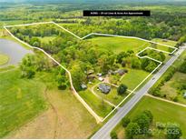 Aerial view of 29 acre property with trees, pond, road, and home highlighted by a white boundary line at 4896 Pageland Hwy, Lancaster, SC 29720