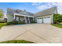 Charming home featuring a welcoming front porch and a two-car garage, set against a manicured lawn at 557 Luther Dr, Iron Station, NC 28080