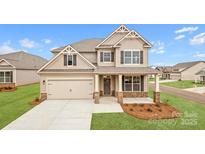 Charming two-story home with a manicured lawn, attached garage, and inviting covered front porch at 7035 Butternut Oak Ter, Huntersville, NC 28078