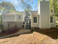 View of the home with light grey siding and stone foundation, accented by lush landscaping at 8000 Briardale Dr, Charlotte, NC 28212