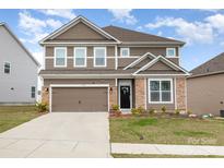 Well-maintained two-story home with brown siding, stone accents, a two-car garage and nice landscaping at 9727 White Chapel Nw Dr, Concord, NC 28027