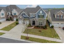 Charming two-story home featuring stone accents, a well-manicured lawn, and an attached two-car garage at 1005 Argentium Way, Waxhaw, NC 28173