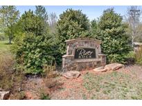Stone 'River Rock' community sign surrounded by lush greenery, creating an inviting entrance at 123 Pumice Dr, Statesville, NC 28625