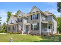 Charming two-story brick home with white trim, a welcoming porch, manicured lawn, and American flag at 3011 Waxhaw Crossing Dr, Waxhaw, NC 28173