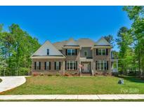 Beautiful two-story brick home with manicured lawn, black shutters, and a welcoming front porch at 3011 Waxhaw Crossing Dr, Waxhaw, NC 28173