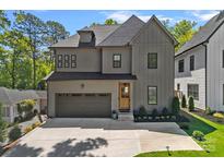 Charming two-story home featuring a light gray exterior, a two-car garage, and lush landscaping at 3228 E Ford Rd, Charlotte, NC 28205